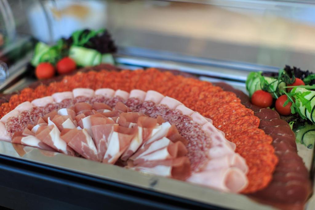Dažādu gaļas šķēļu un dārzeņu kompozīcija, kas izvietota uz galda. Sastāv no šķiņķa, salami un citiem gaļas produktiem, ko papildina svaigi dārzeņi.