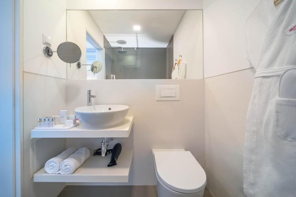 Mūsdienīgs vannas istabas interjers ar elegantu izlietni, higiēnas piederumiem un dvieļiem. Balta krāsa un minimālistisks dizains rada svaigu un tīru atmosfēru.