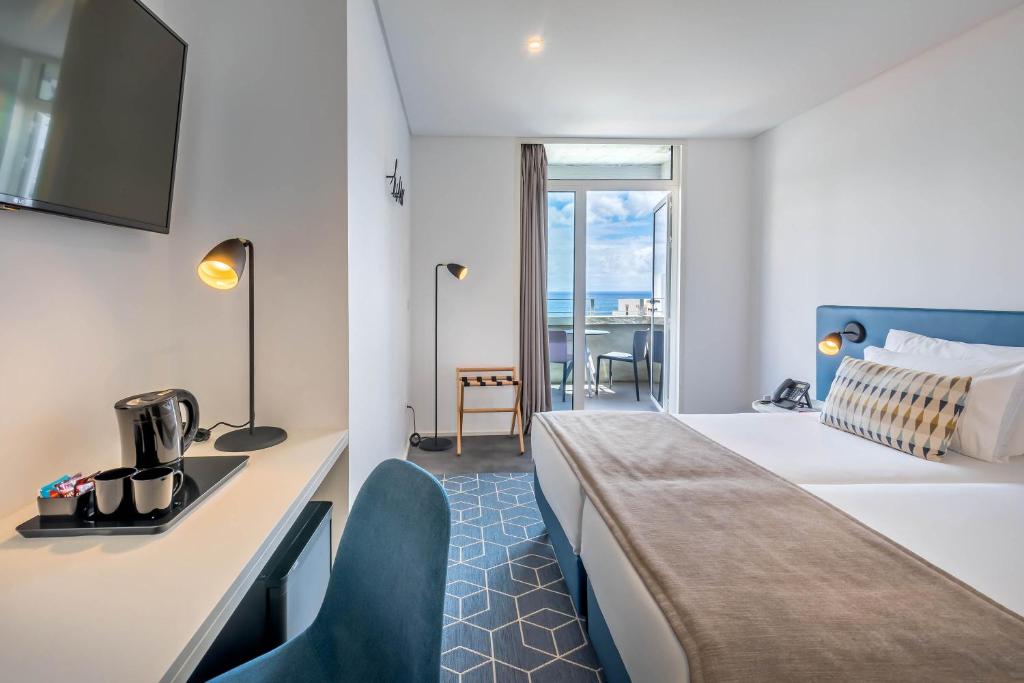 Mūsdienīgs viesnīcas numurs ar skatu uz jūru, aprīkots ar televizoru, rakstāmgaldu un kafijas automātu. Gaisma un ērta mēbele veicina relaksējošu atmosfēru.