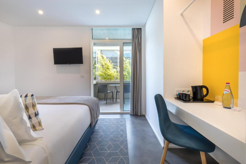 Mūsdienīgs viesnīcas numurs ar gultu, televizoru un rakstāmgaldu, kurā ir krēsls un tēja. Lieliski apgaismots ar logu, kas ved uz balkonu ar skatu uz dārzu.