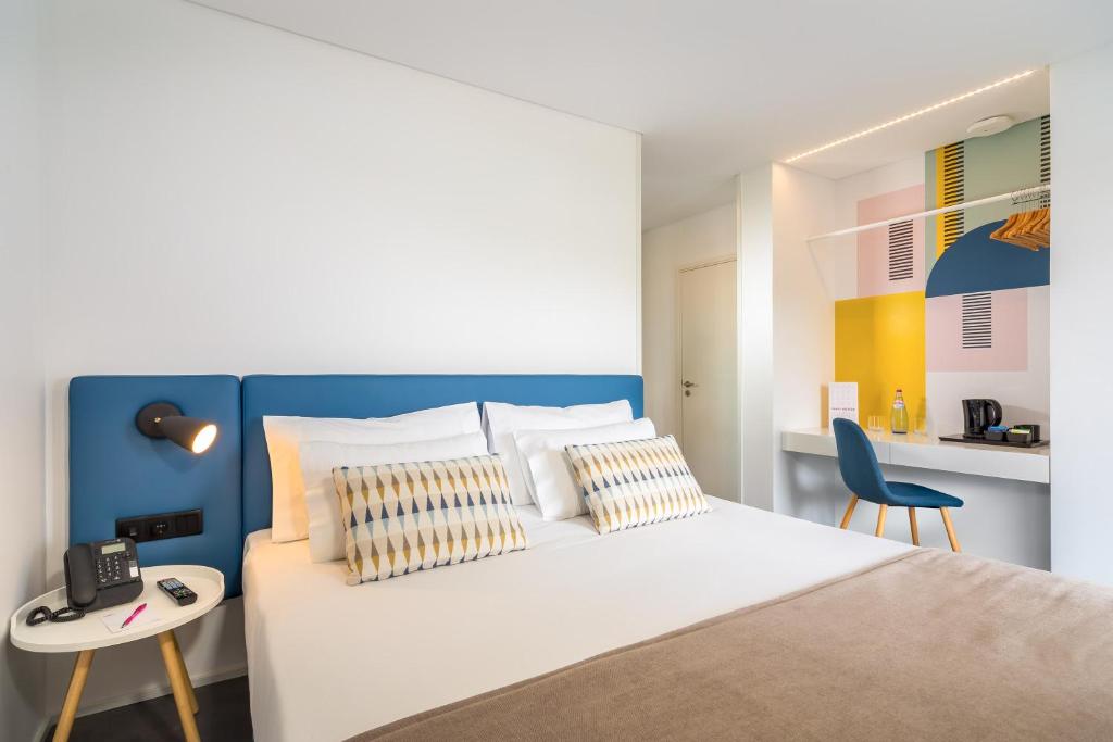 Mūsdienīgs viesnīcas numurs ar gaišu dizainu, ērtiem gultas veļiem un krāsainu sienu apdari. Numurā ir rakstāmgalds un koka krēsls, kas piedāvā patīkamu atpūtas vietu.