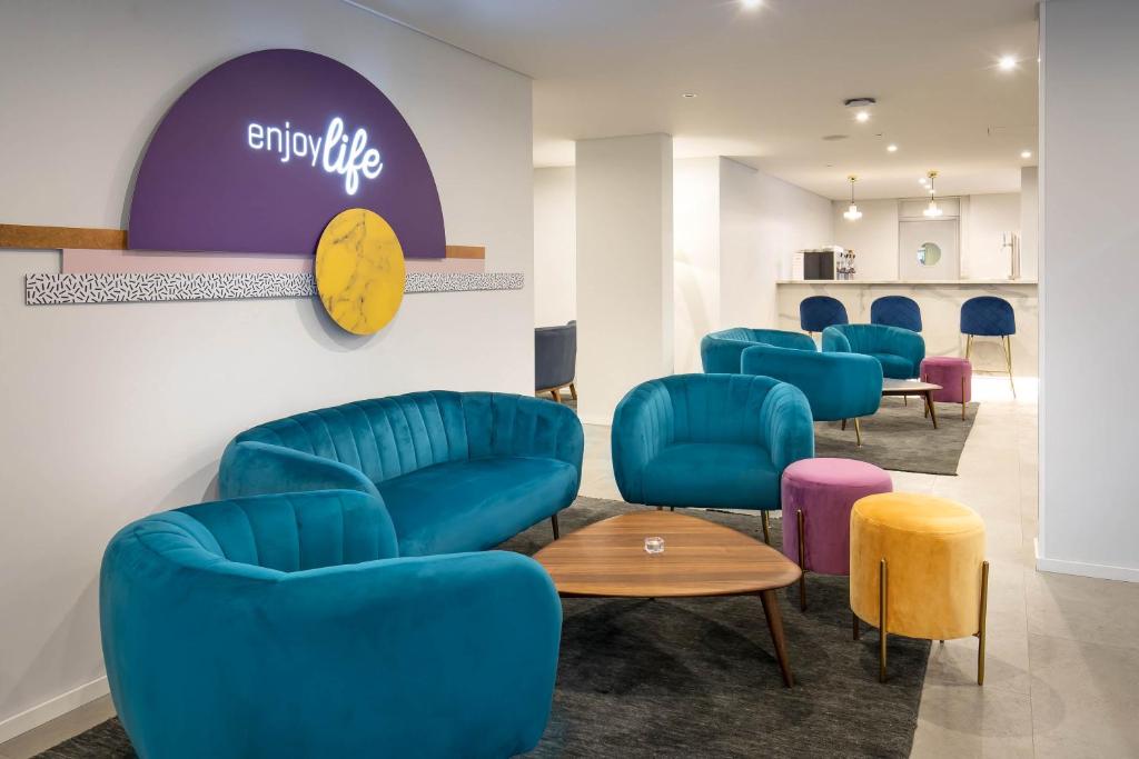 Mūsdienīgs un stilīgs atpūtas telpas interjers ar krāsainām dīvānām un krēsliem, kas aicina izbaudīt dzīvi. Uzsvars uz komfortu un estētiku, radot patīkamu atmosfēru.