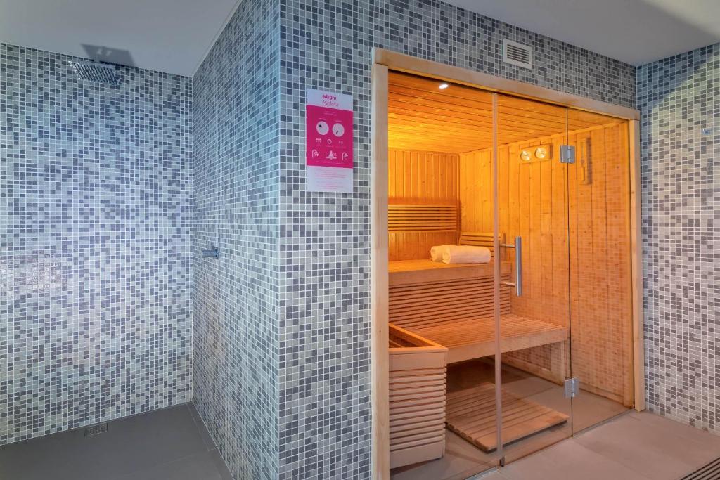 Mūsdienīga sauna ar koka interjeru un stikla durvīm, iestatīta mozaīkas sienu vidē. Ideāla vieta relaksācijai un labsajūtai.