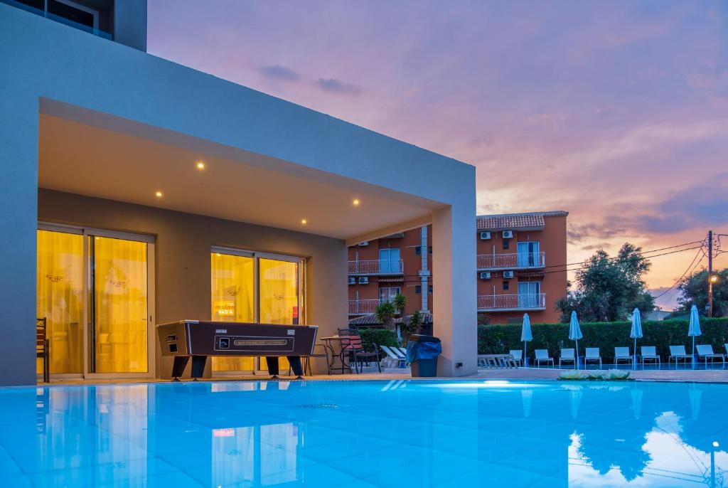 Mūsdienīgs viesnīcas ārējais baseins ar skaistu saulrietu un apgaismotu terasi. Vides komforta sajūta ar zilo ūdeni un atpūtas krēsliem.
