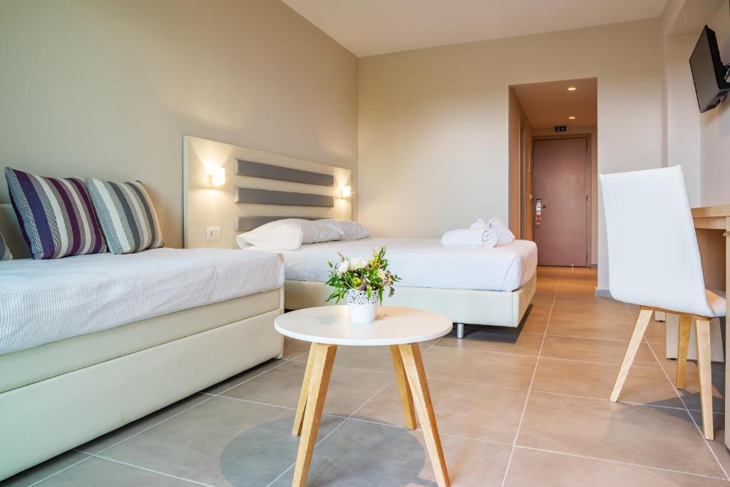 Mūsdienīgs viesnīcas numurs ar divām gultām, minimālistisku dizainu un gaismas apgaismojumu, iekārtots ar rakstainām spilveniem un mazu galdiņu ar ziediem.