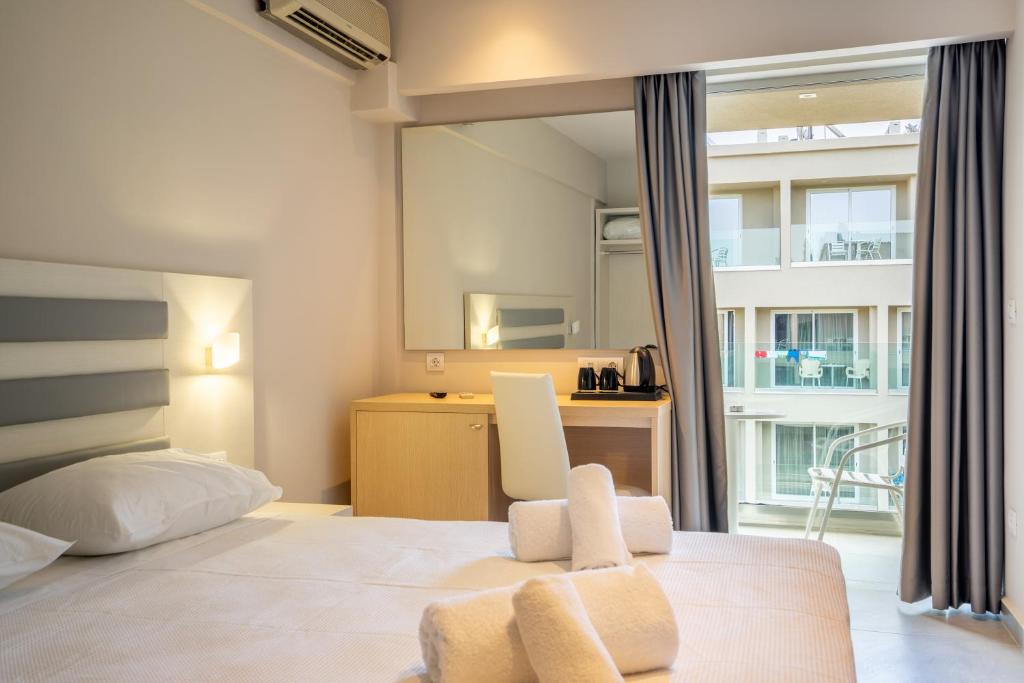 Mūsdienīga viesnīcas numura interjers ar gultu, rakstāmgaldu un skatu uz terasi. Numurā ir gaišas krāsas un mūsdienīgi aksesuāri, kas nodrošina komfortablu atmosfēru.