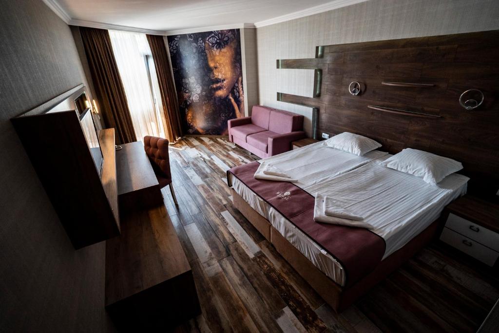 Mūsdienīgs viesnīcas numurs ar divām gultām, dīvānu un elegantu koka apdari, kas papildināts ar māksliniecisku sienas gleznojumu. Logi nodrošina dabisko apgaismojumu un skatu uz ārpusi.