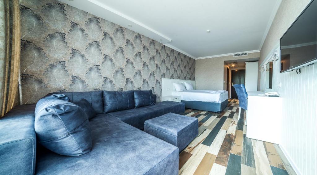 Mūsdienīgs viesnīcas numurs ar ērtu dīvānu, spilveniem un koka grīdu, kas rada siltu atmosfēru. Telpā ir gultas zona un televizors, piedāvājot komfortablu atpūtu.