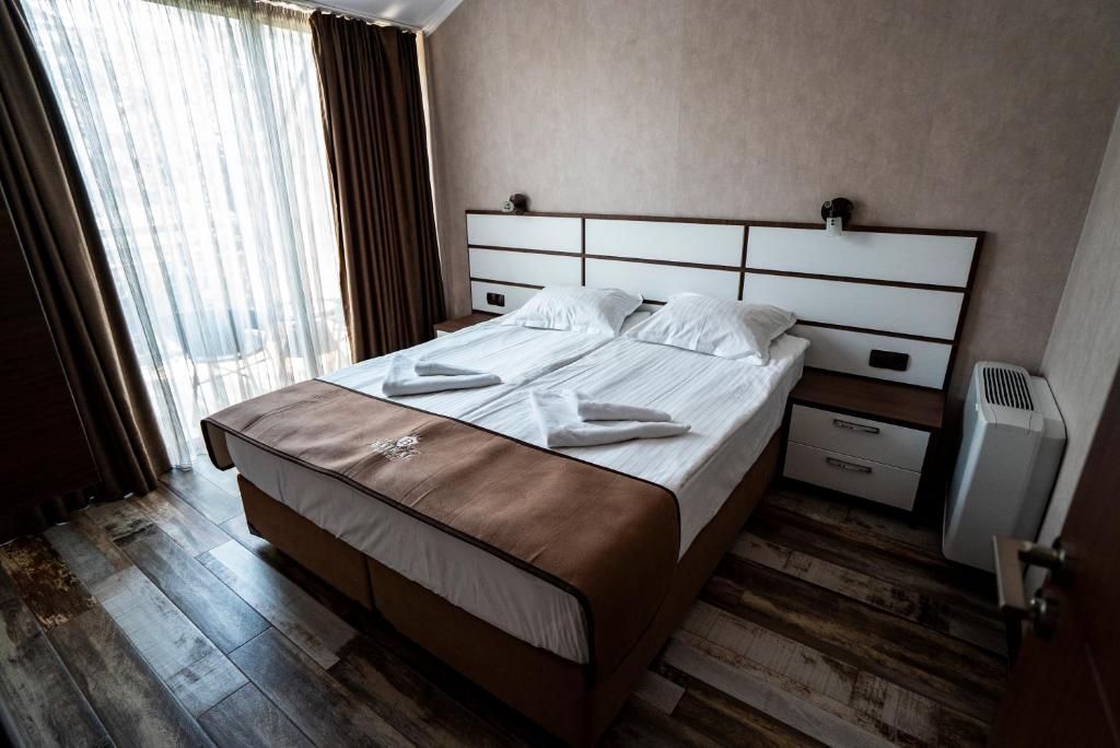 Mūsdienīga viesnīcas numura iekārtojums ar divām gultām, koka grīdu un lieliem logiem, kas nodrošina dabisko apgaismojumu. Interjers ir elegants un ērts, radot relaksējošu atmosfēru.