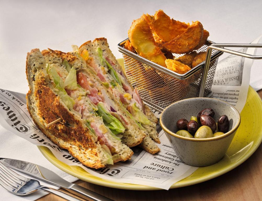 Garšīgs sviestmaize ar dārzeņiem, pasniegta ar ceptiem kartupeļiem un olīvām. Ideāls ēdiens, lai izbaudītu gardas maltītes.