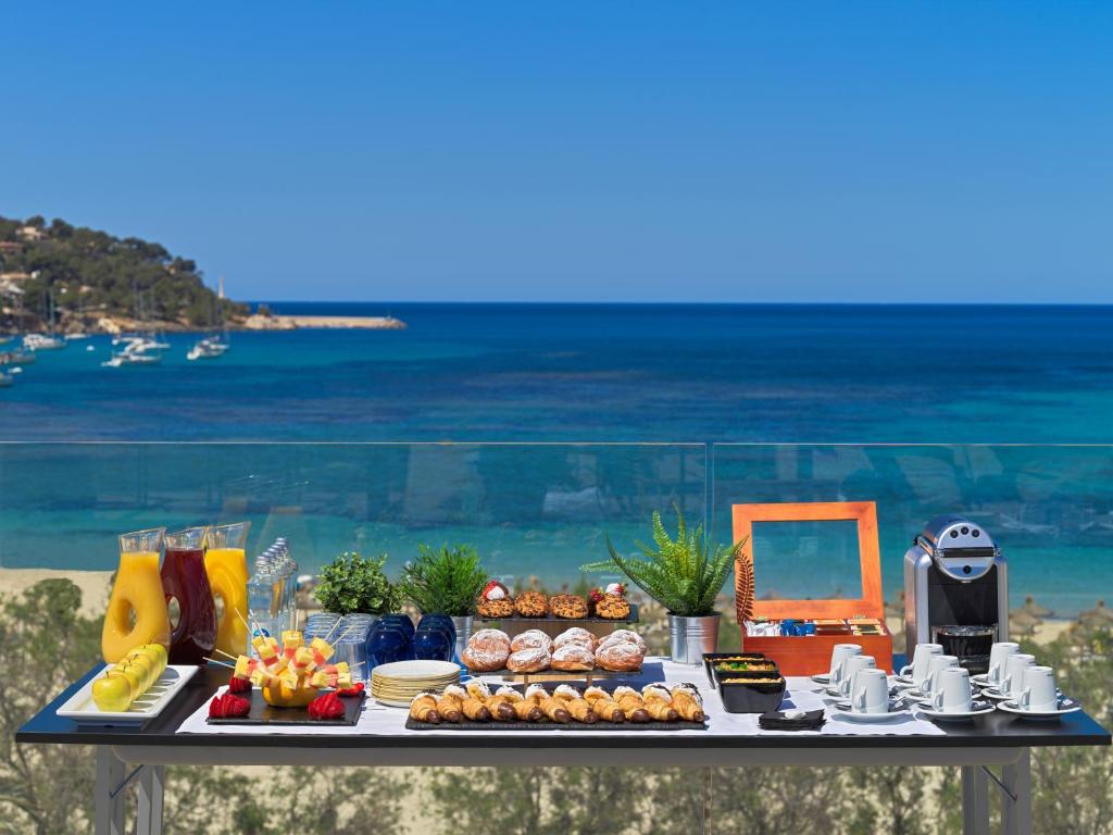 Broka ar dažādiem izstrādājumiem un dzērieniem, novietota uz galda ar skatu uz jūru. Ideāla vieta relaksācijai un brokastīm.