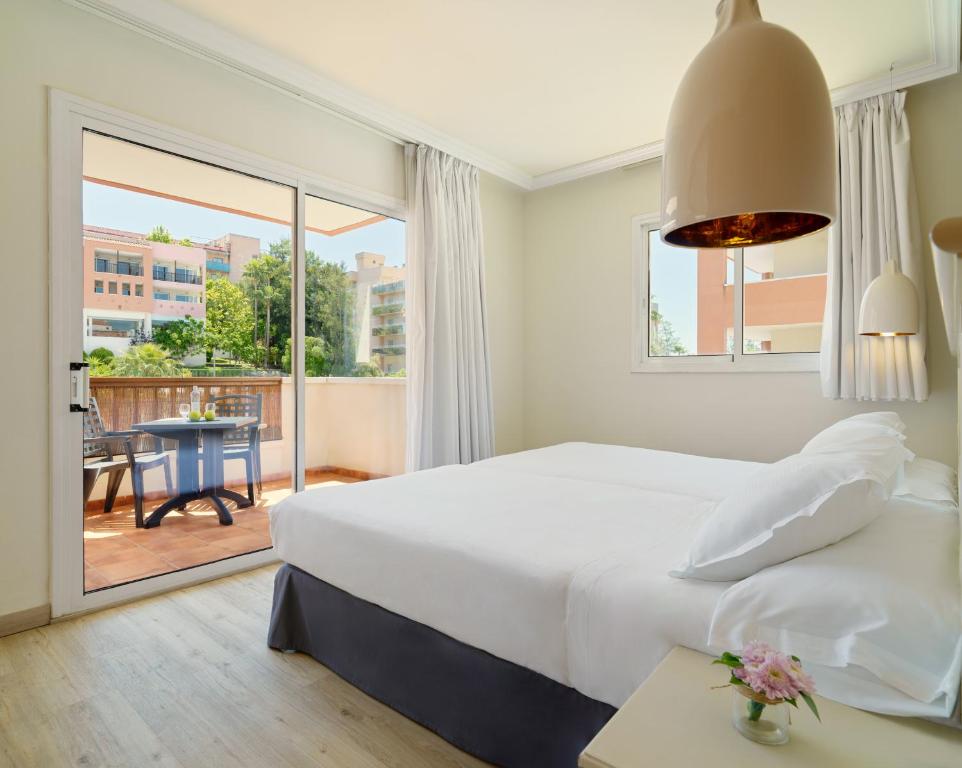 Mūsdienīgs viesnīcas numurs ar plašu logu, kas ved uz terasi, kur atrodas galdiņš un krēsli. Numurā ir ērta gulta un stilīgas gaismas.