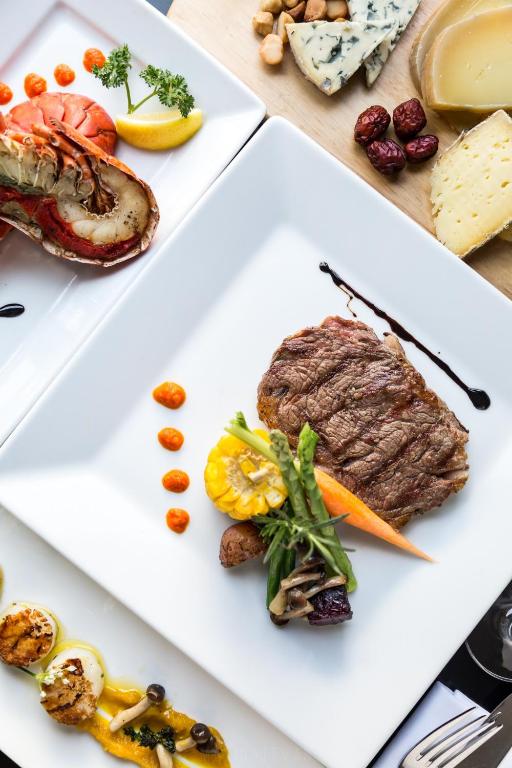 Gourmet maltīte, kas ietver sulīgu steiku ar dārzeņiem un garnelēm, dekorēta ar krāsu un mērci.