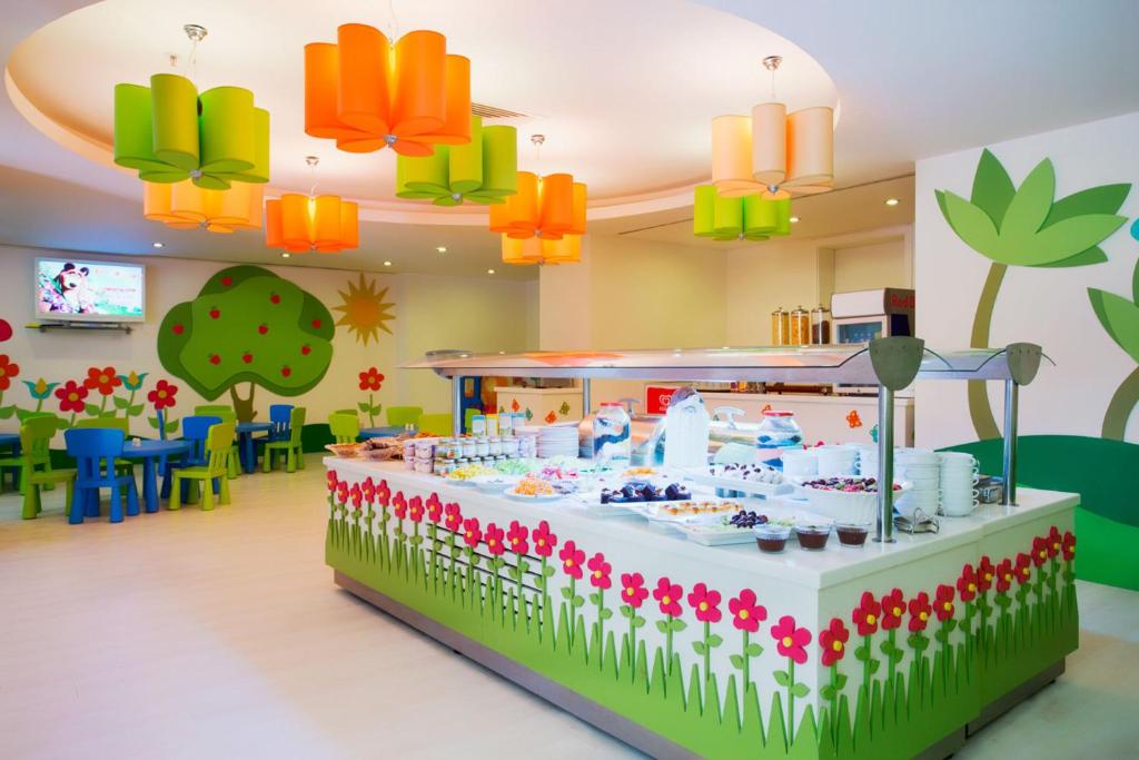 Krāsainā bērnu kafejnīca ar rotaļīgu interjeru, ziedu un koku apdari, piedāvā gardumus bufetē. Spilgti lampu toņi un ērtas krēsli rada draudzīgu atmosfēru.