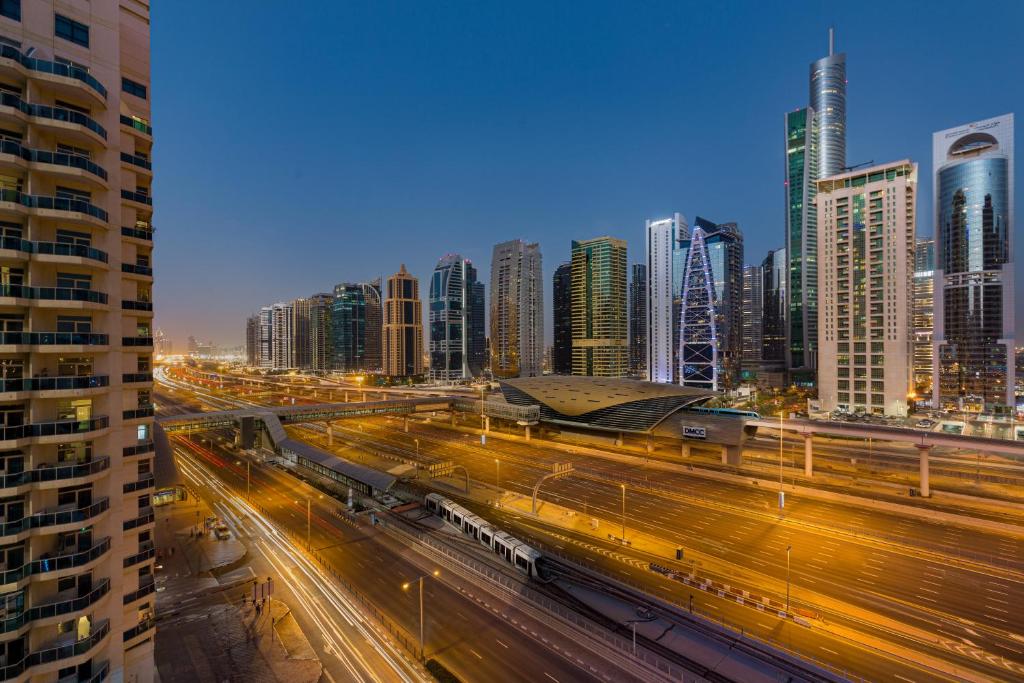 Mūsdienīga pilsētas ainava ar augstceltnēm un gaismas ceļiem Dubaijā, uzsverot dinamisko urbanizāciju un moderno arhitektūru.