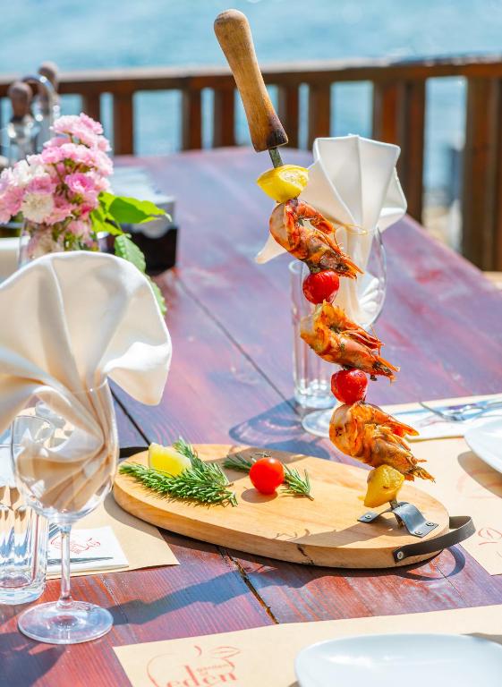 Grilēti garneles uz iesma ar citronu un dārzeņu dekorāciju, pasniegti pie elegantas galda klāšanas.