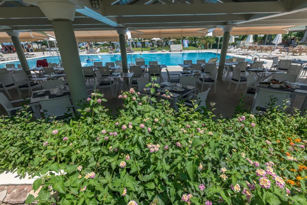 Peldbaseina zona ar ēdināšanas vietu un ziediem priekšplānā, radot relaksējošu atmosfēru. Ideāla vide atpūtai un izbaudīšanai.