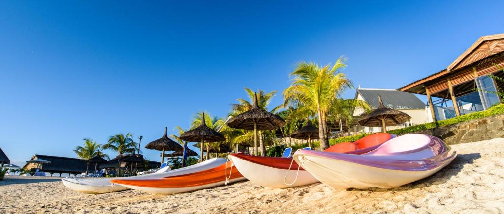 Sauļošanās pludmalē ar krāsainām laivām un palmām, kas nodrošina ēnu. Skaists skats uz zilo debesu fonu un pludmales ainavu.