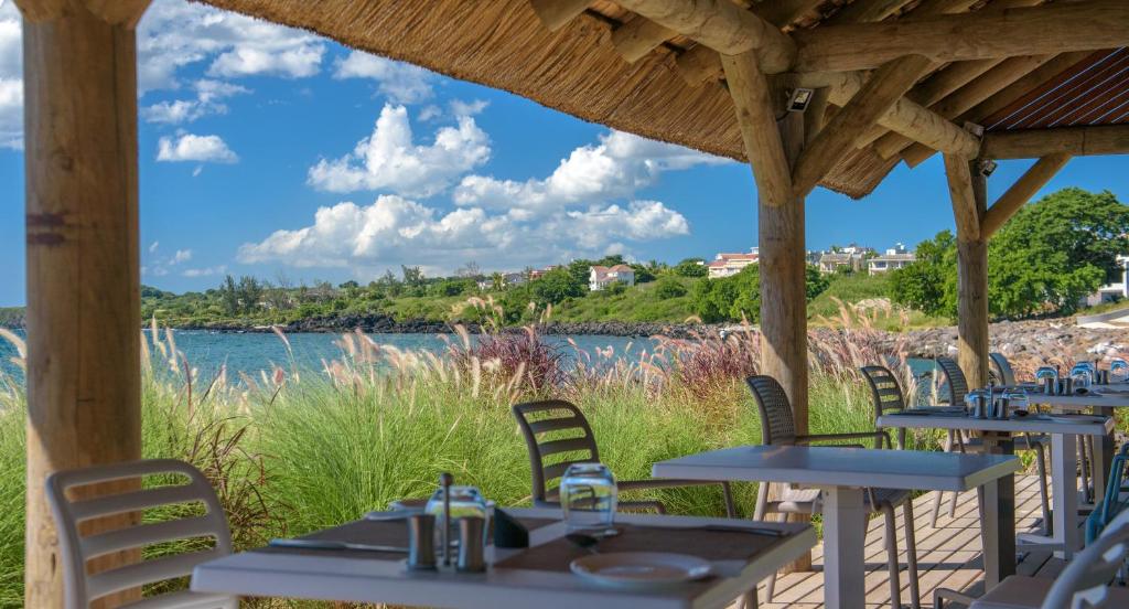 Balto smilšu pludmales restorāns ar skatu uz jūru un zaļajiem pakalniem, kas ieviesti ar ziedu stādījumiem. Ideāla vieta relaksācijai un ēdiena baudīšanai brīvā dabā.