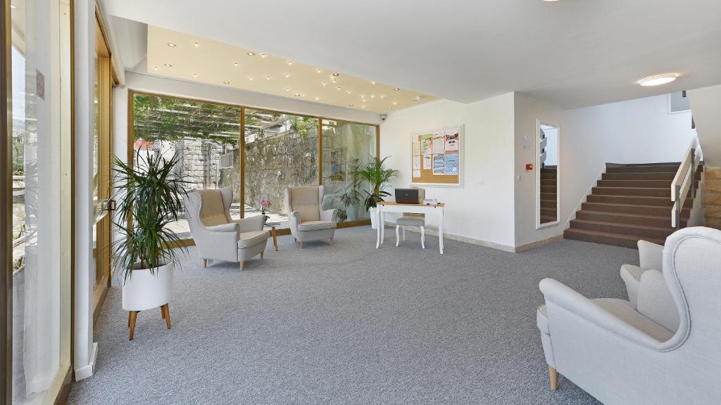 Gaiša un moderna uzņemšanas telpa ar divām ērtām krēslām, galdu un augiem. Labi apgaismota, ar lieliem logiem, kas nodrošina skatu uz dārzu.