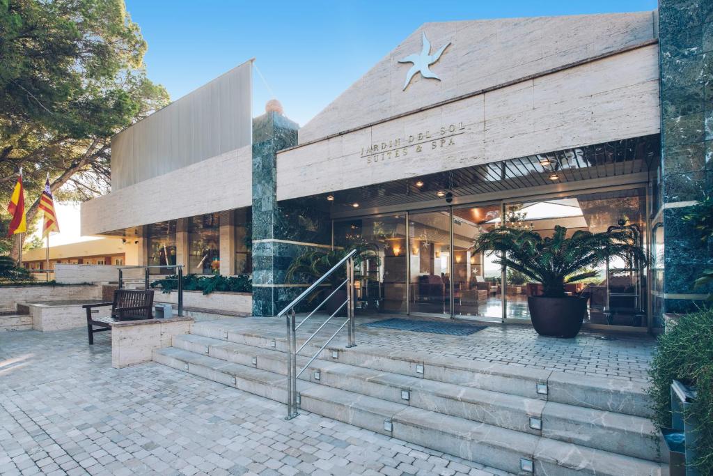 Mūsdienīgas viesnīcas ieeja ar stikla durvīm, akmens apdari un zaļiem augiem, kas rada patīkamu atmosfēru. Viesnīca "Jardín del Sol Suites & Spa" piedāvā komfortu un relaksāciju.