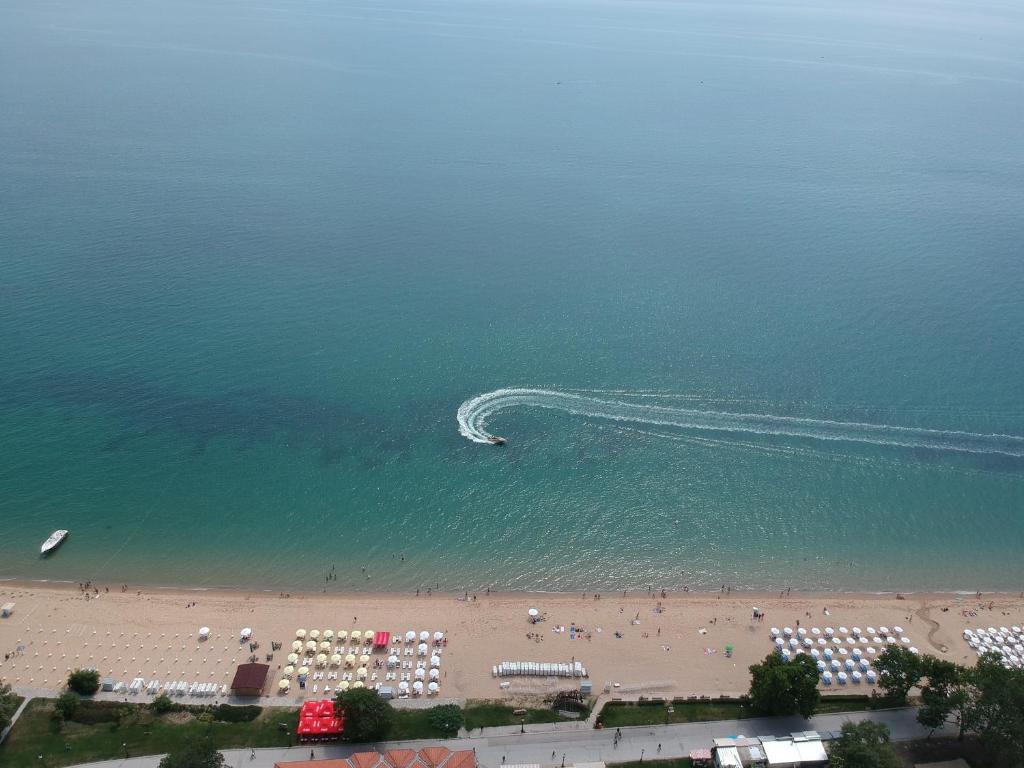 Pludmale ar smiltīm un saules lietām, kurā redzama laiva ar pēdām ūdenī. Fons ir mierīgs jūras skats.