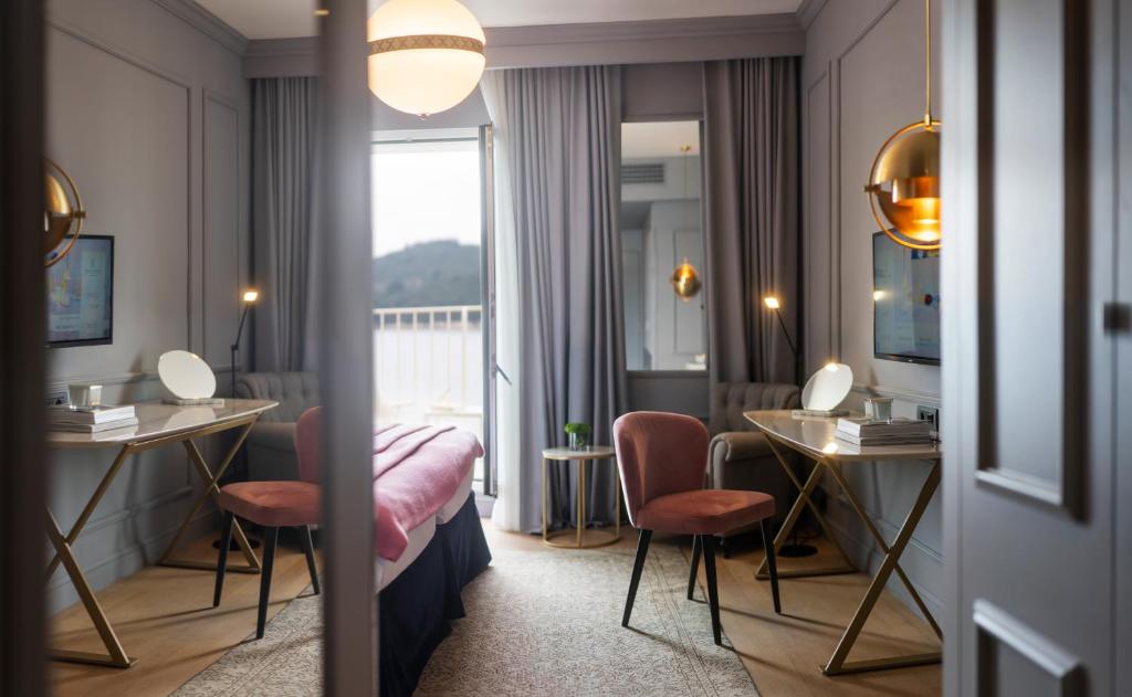 Mūsdienīgs viesnīcas numurs ar elegantu interjeru, iekārtots ar stilīgām mēbelēm un gaismas avotiem, kas rada patīkamu atmosfēru. Logi paver skatu uz dabu, nodrošinot gaismu un komfortu.