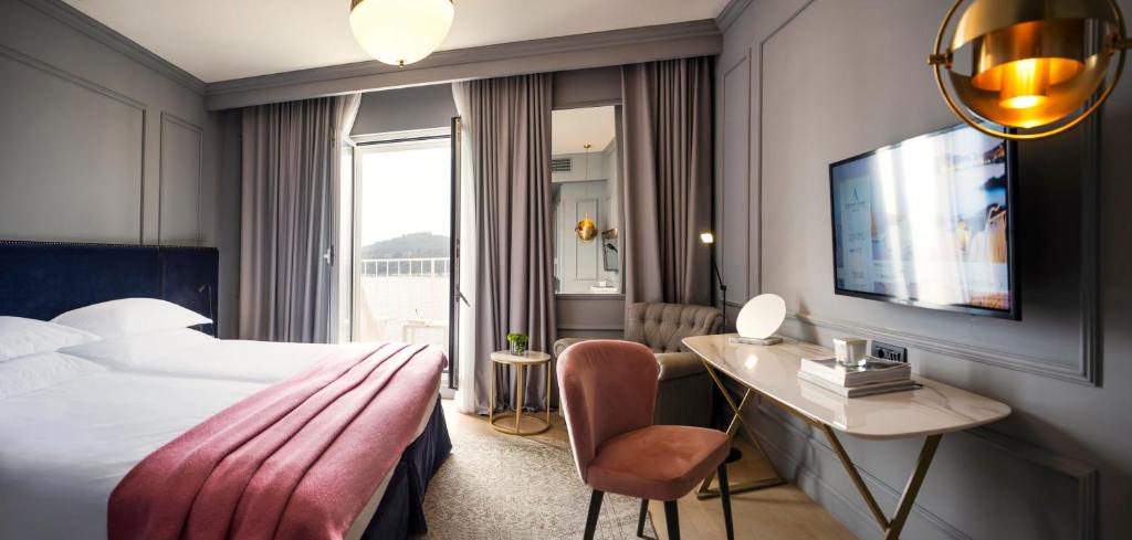 Mūsdienīgs viesnīcas numurs ar divām gultām, stilīgu darba galdu un televizoru. Logi ļauj ienākt dabiskajai gaismai, radot siltu un aicinošu atmosfēru.