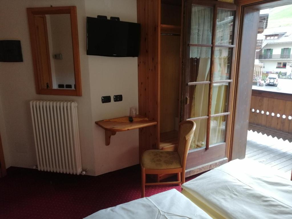 Istaba ar koka elementiem, televizoru uz sienas un piekļuvi balkonam. Telpā ir arī galds un krēsls, kā arī radiatora sildītājs.