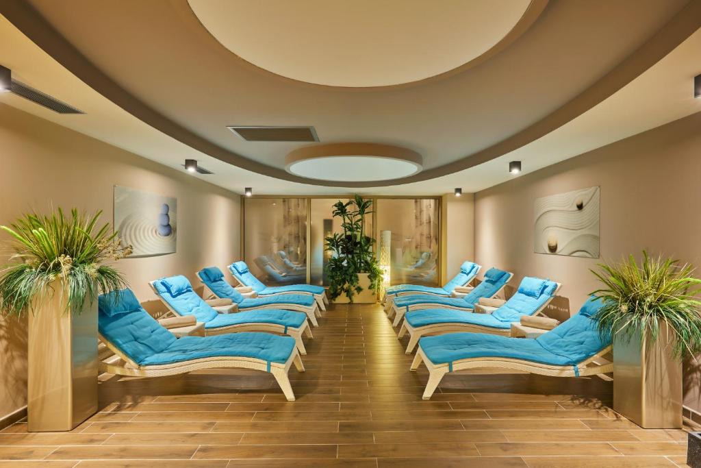 Mūsdienīgs spa atpūtas telpa ar zilām guļamkrēslām un augu dekoru, nodrošinot relaksējošu atmosfēru. Telpa ar gaišu apgaismojumu un elegantu dizainu.