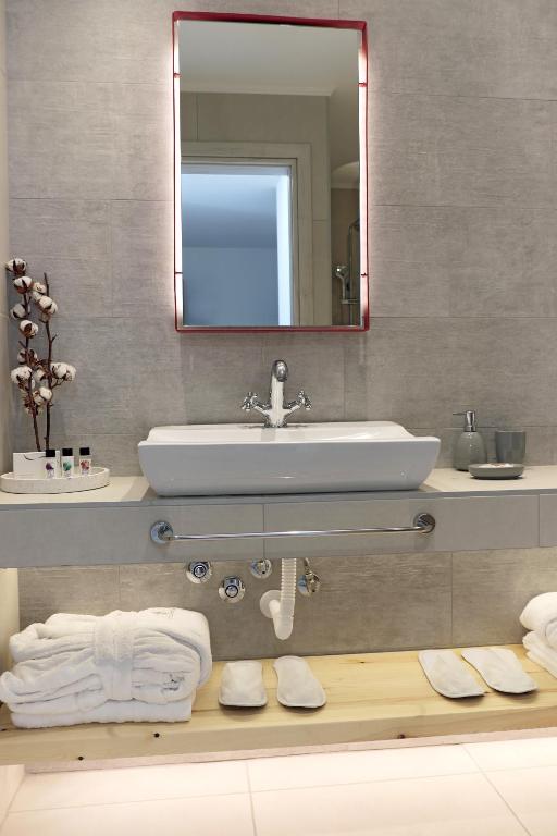 Mūsdienīgs vannas istabas interjers ar modernu izlietni, spoguli un dvieļiem, kas izvietoti uz koka plaukta. Uz galda ir arī higiēnas līdzekļi un dekoratīvi elementi.