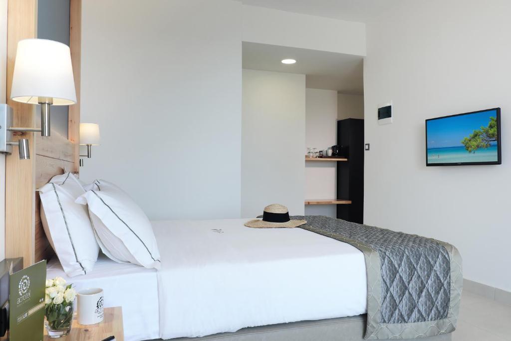 Moderns viesnīcas numurs ar ērtu gultu, stilīgu interjeru un televizoru. Pie galda ir kafijas pagatavošanas iekārta un glāzes, radot relaksējošu atmosfēru.