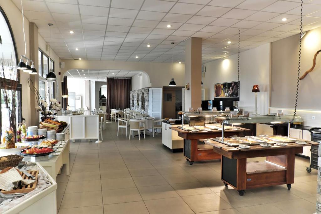 Mūsdienīgs restorāns ar gaišu interjeru un bufetes galdiem, kas piedāvā dažādus ēdienus. Telpa ir plaša un eleganta, ar daudzām sēdvietām un moderna apgaismojuma risinājumiem.