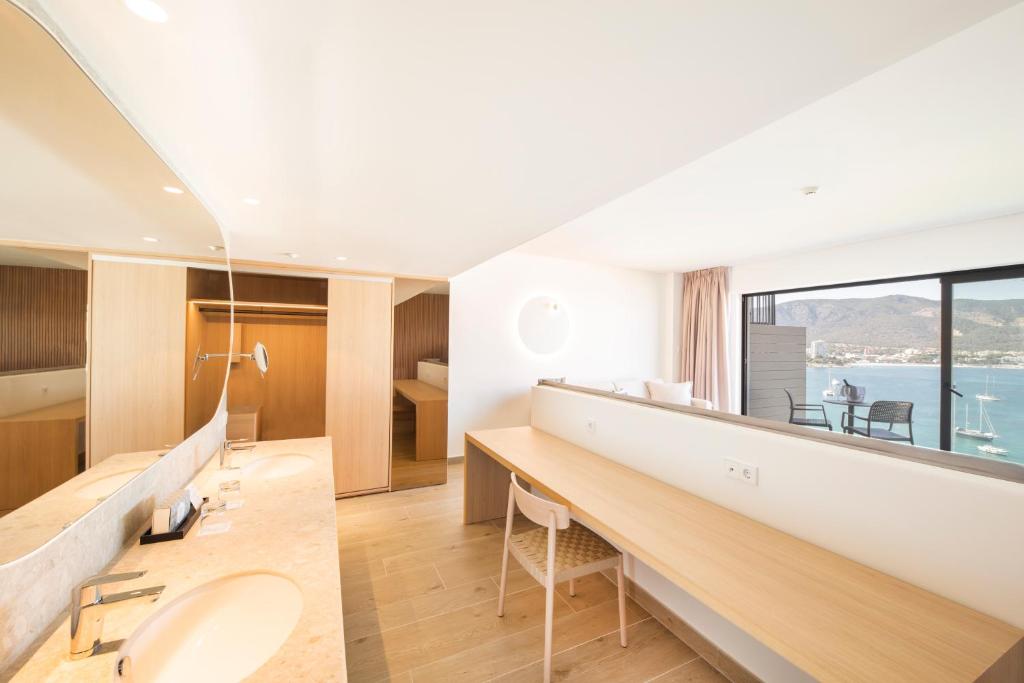 Mūsdienīga viesnīcas numura interjers ar koka akcentiem, plašu rakstāmgaldu un skatu uz jūru. Numurā ir divas izlietnes un liels spogulis, radot komfortablu un stilīgu atmosfēru.