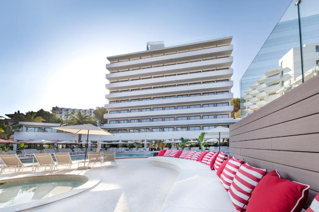 Mūsdienīgs viesnīcas komplekss ar baseinu un sauļošanās gultām, ko ieskauj palmām un sauļošanās lietussargiem. Sarkanbalti spilveni pie baseina piešķir stilīgu un komfortablu atmosfēru.