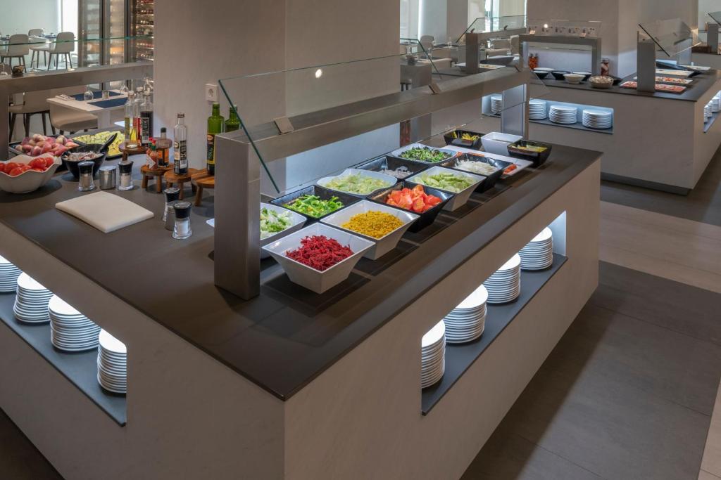 Moderns pašapkalpošanās bufete ar dažādām dārzeņu un salātu izvēlēm, garšvielām un eļļām. Gaišas plāksnes un higiēniskas uzglabāšanas vietas.