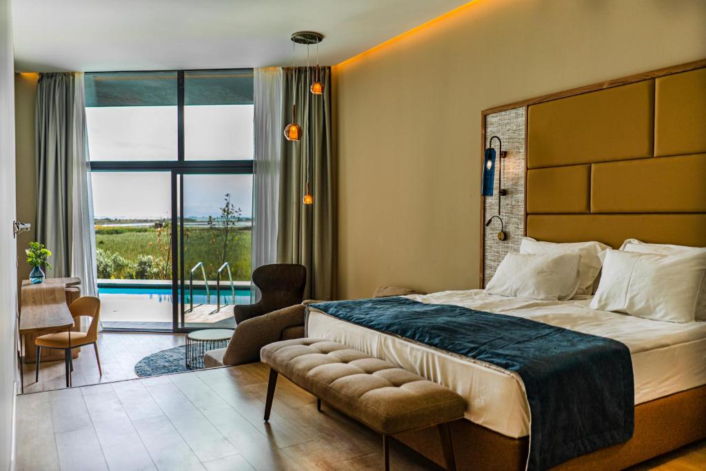 Mūsdienīgs viesnīcas numurs ar plašu logu, kas paver skatu uz dabu un privātu baseinu. Interjers ir elegants ar ērtiem mēbeļu elementiem un siltām gaismām.