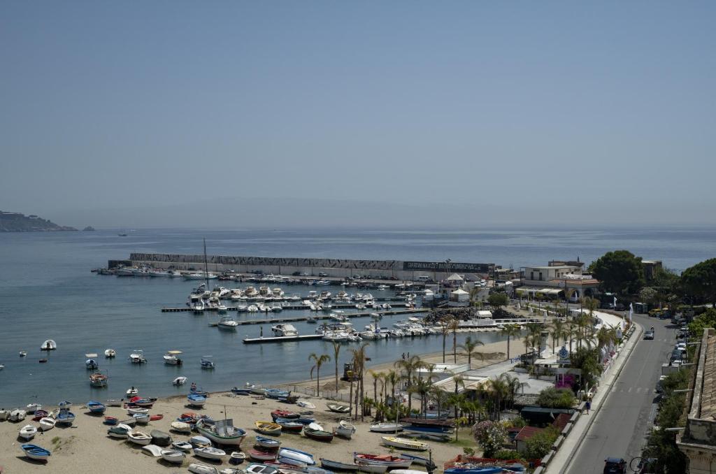 Osta ar daudziem kuģiem un laivām, blakus pludmalei un promenādei. Skats uz mierīgu jūru un blakus esošo apbūvi.