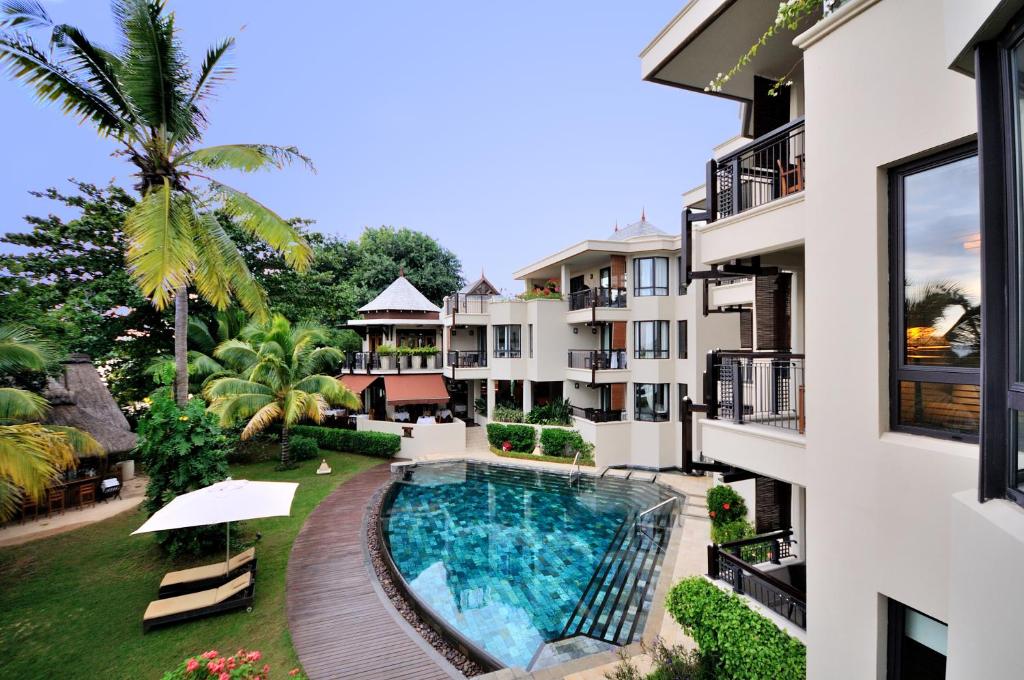 Eleganta viesnīca ar baseinu un tropisku ainavu, kas ietver palmām un sulīgām zaļām augiem. Ideāla vieta atpūtai un relaksācijai.
