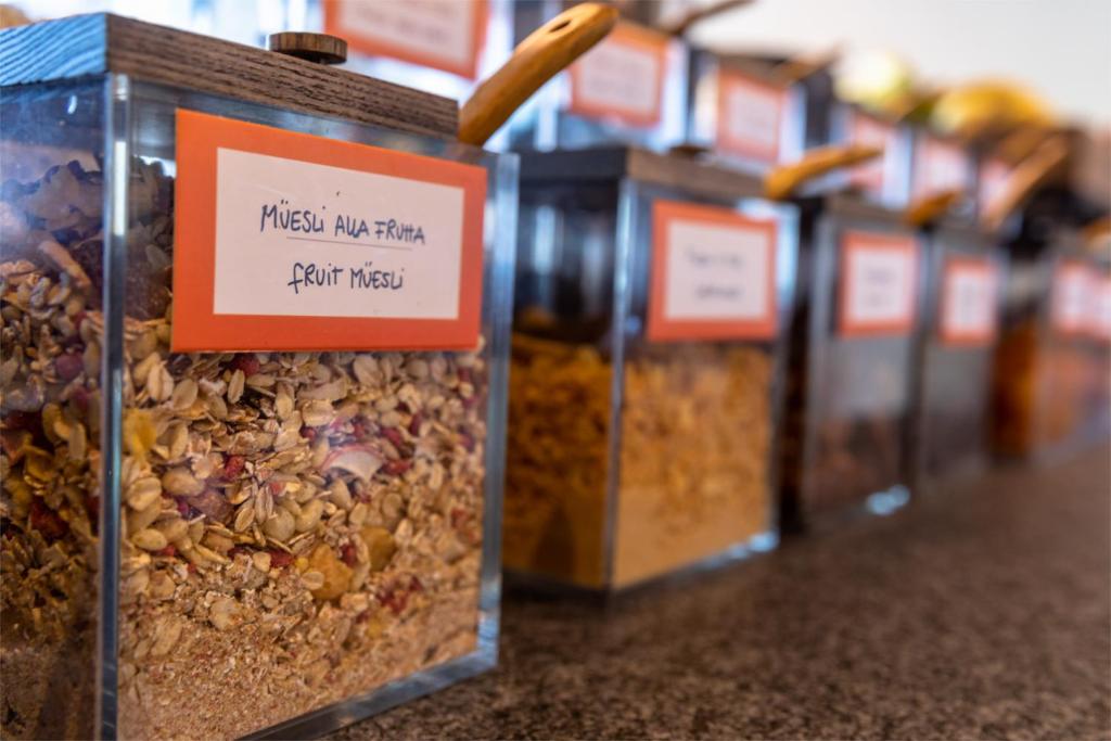 Mūsuli un graudaugi organizētās burkās ar marķējumiem, kas norāda uz dažādiem muesli veidiem, piemēram, augļu muesli. Ideāli piemērots brokastīm vai uzkodām.