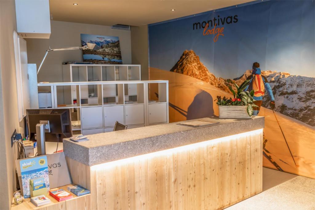 Mūsdienīga viesnīcas reģistratūra ar akcentu uz kalnu ainavām un siltu apgaismojumu. Galda virsma ir no dabīgā koka, un fons attēlo kalnu slēpotāju.