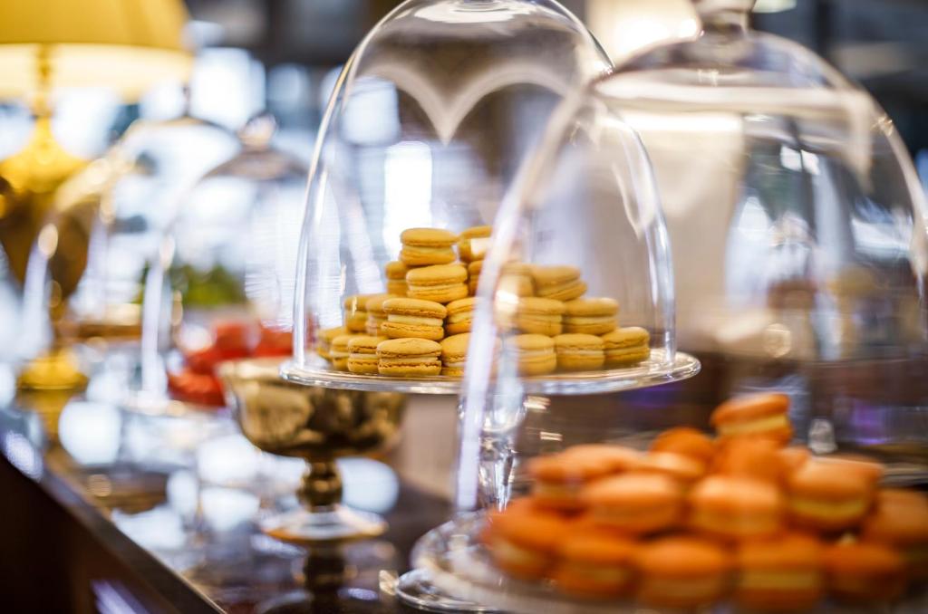 Saldumu stends ar glabāšanas kupoliem, kas satur dažādu krāsu makaronus, tostarp dzeltenus un oranžus. Elegants deserts, kas pievilina ar savu izskatu un garšu.