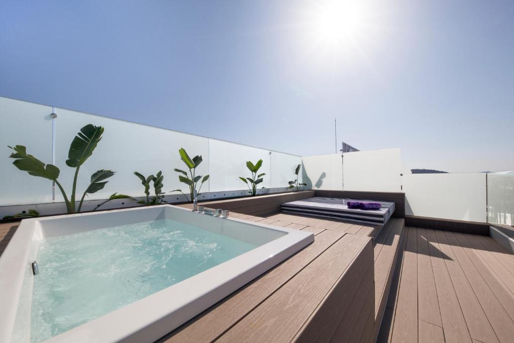 Stilīga terase ar džakuzi un saulainu skatu, apkārt augi un atpūtas zona ar gultu. Ideāla vieta relaksācijai un atpūtai.