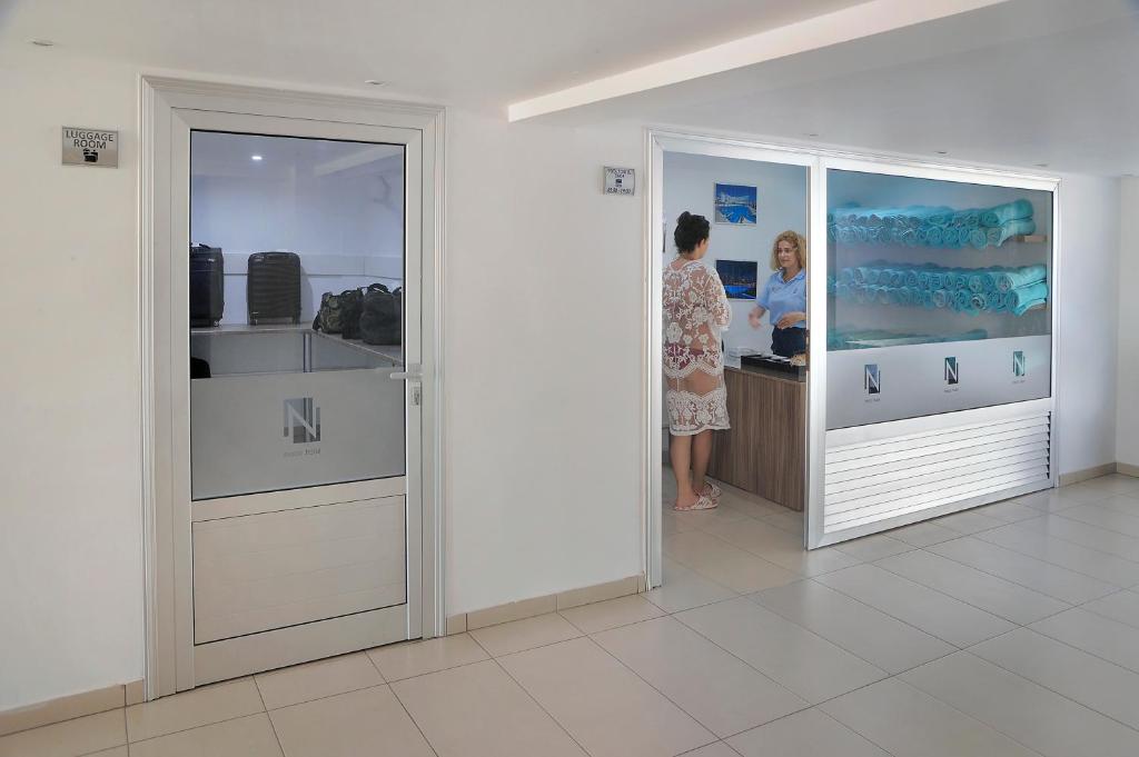 Recepcija viesnīcā ar bagāžas telpu un darbiniekiem, kas apkalpo viesus. Gaisīga un moderna vide, kas nodrošina ērtības ceļotājiem.