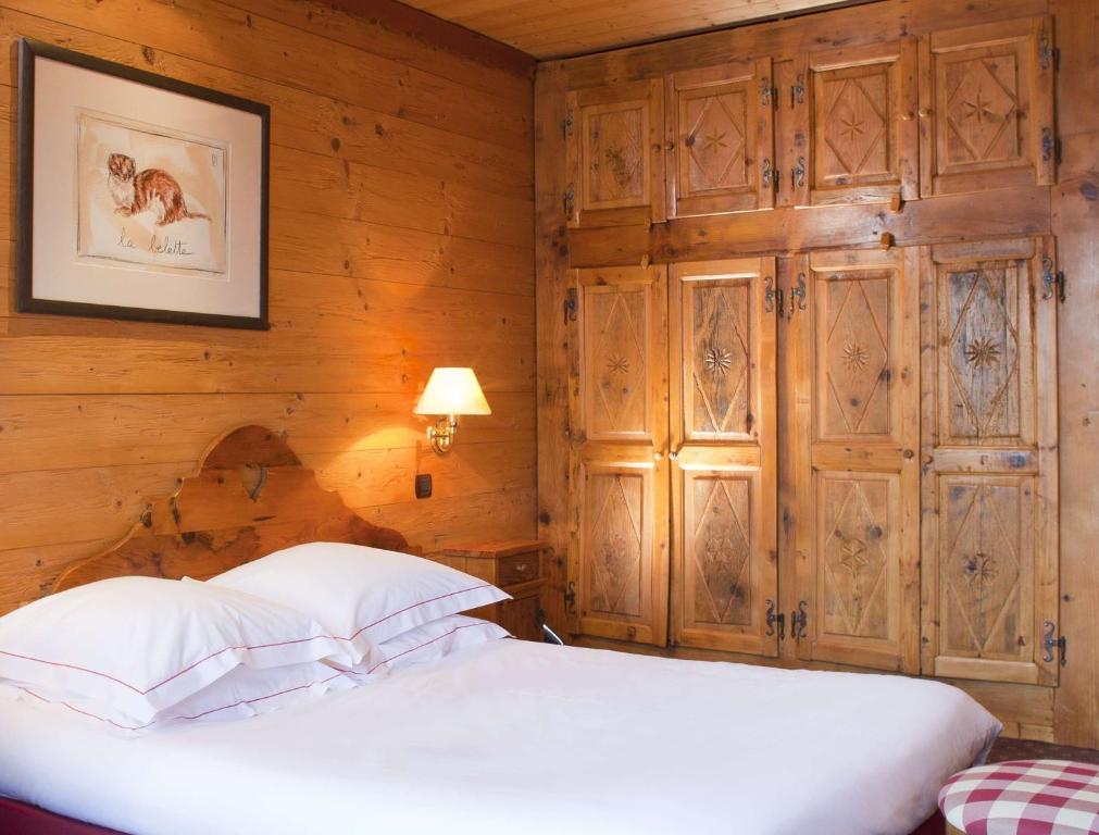 Koka interjers ar gultu un izsmalcinātiem skapjiem, uz sienas ir mākslas darbs. Siltā apgaismojuma gaisma rada mājīgu atmosfēru.