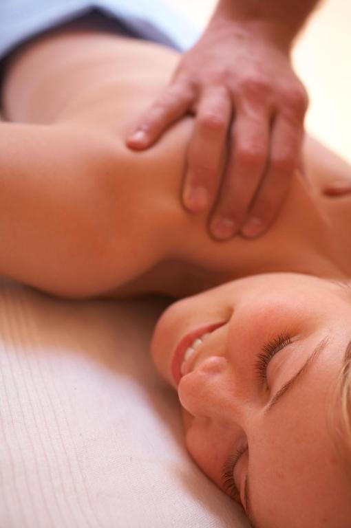 Masažas, kurā redzama sieviete, kas relaksējas uz masāžas galda, izskatās apmierināta un mierīga.