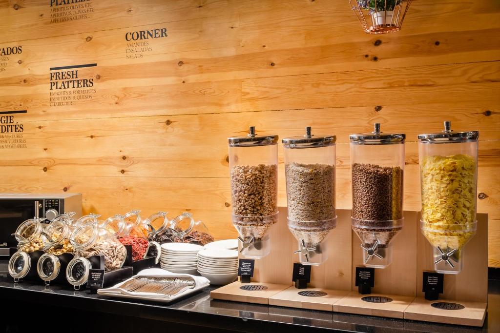 Maltīšu stacija ar dažādiem graudaugiem, riekstiem un žāvētām ogām, kas pasniegta modernā un koka interjerā. Svaigi plāksnes un šķīvji papildina piedāvājumu.