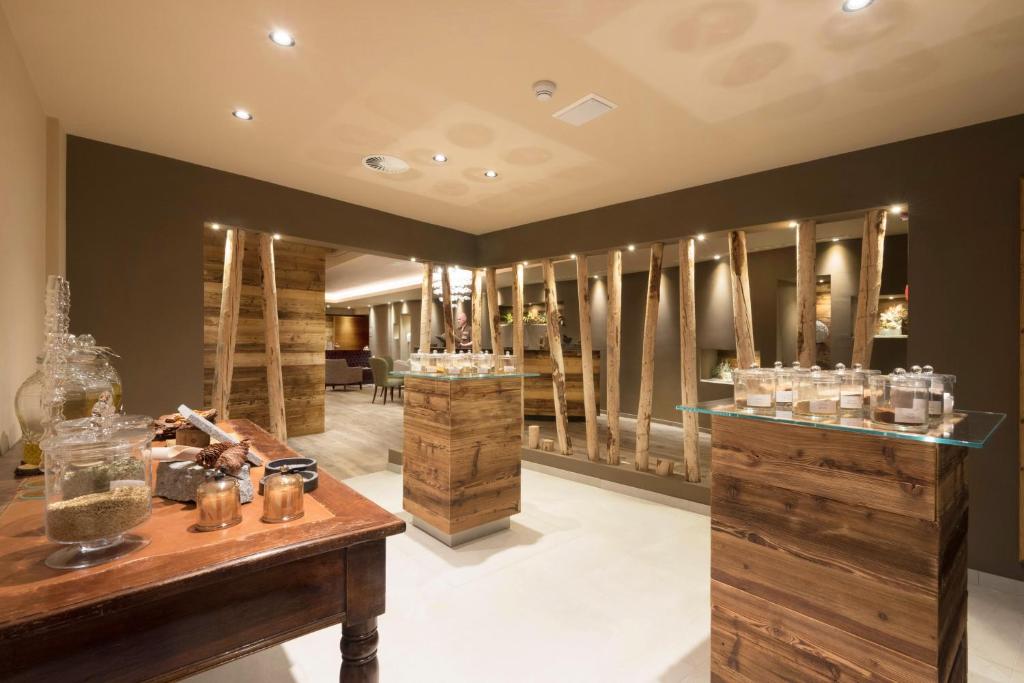 Mūsdienīgs interjers ar koka elementiem un elegantiem stendiem, kas piepildīti ar aromātiskām vielām un dabīgām sastāvdaļām. Telpa ir izgaismota ar siltām gaismām, radot relaksējošu atmosfēru.