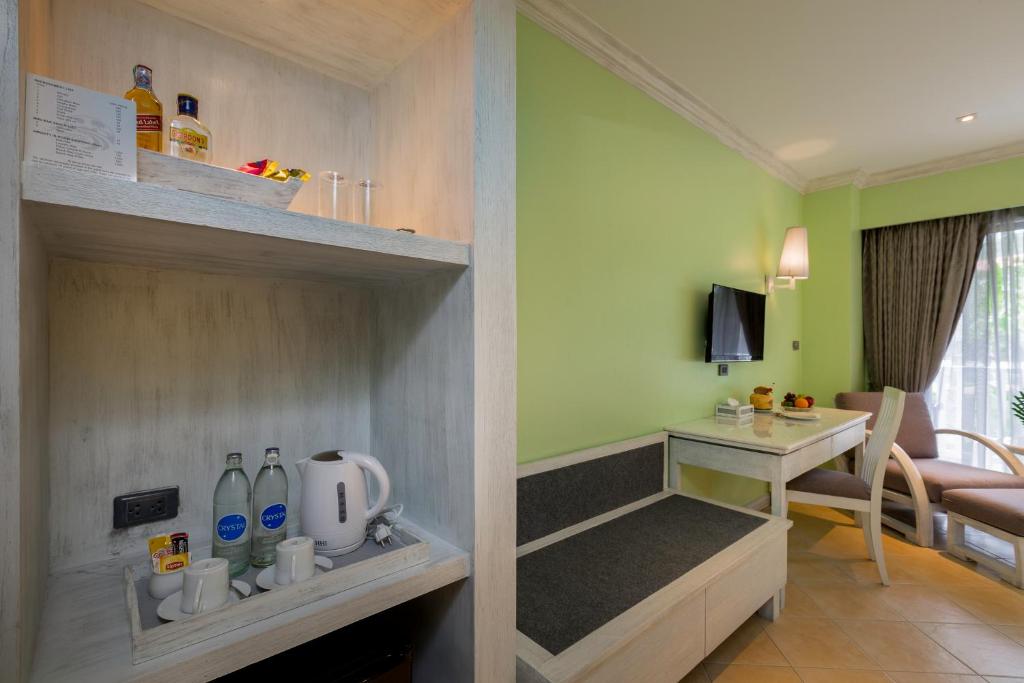 Mūsdienīgs viesnīcas numurs ar zaļām sienām, mini bāru un ērtu sēdvietu. Interjers ir gaišs ar televizoru un galdu, kas papildina relaksējošu atmosfēru.