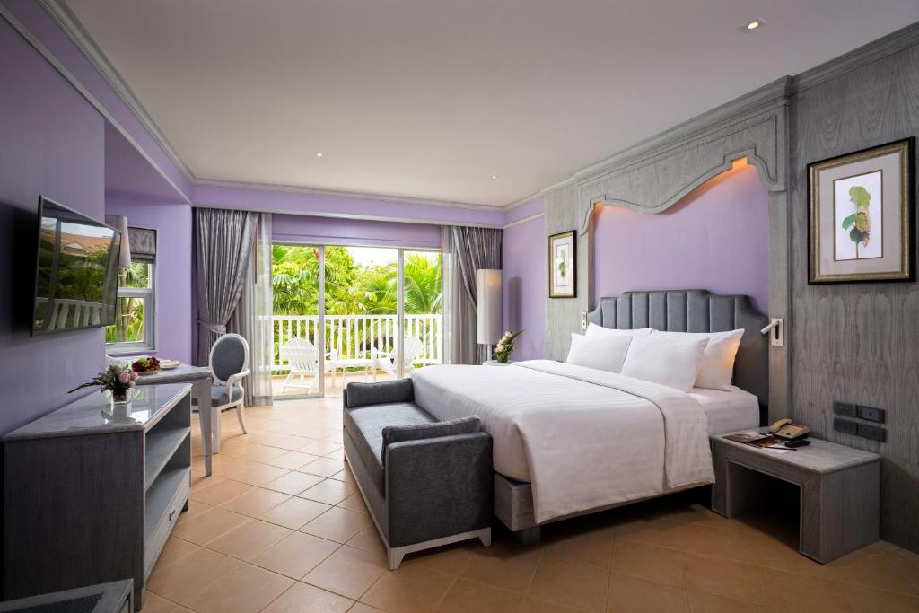 Mūsdienīga viesnīcas numura iekārtojums ar gaiši purpura sienām, ērtu gultu un skatu uz dārzu. Numurā ir televizors, galds un krēsls, radot patīkamu un relaksējošu atmosfēru.